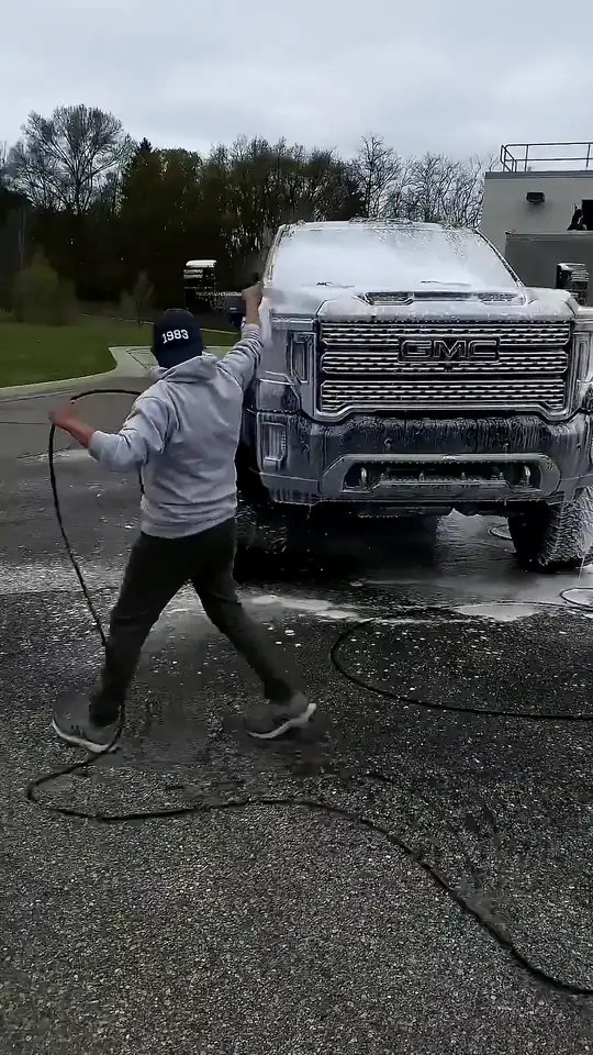 Manrique foam-washing a GMC Sierra HD with a pressure washer