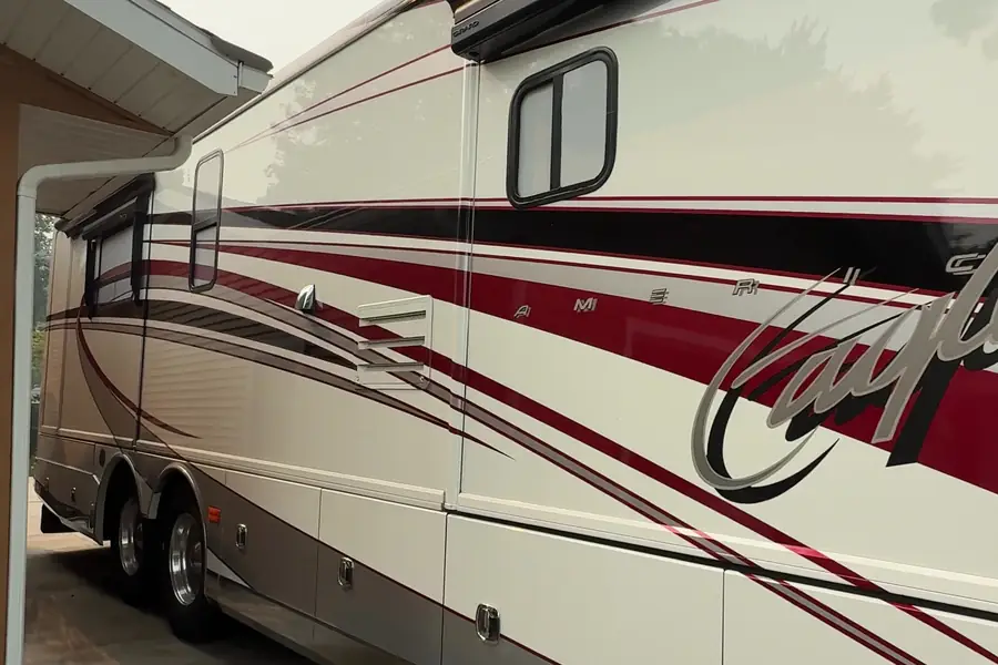 Rear of a Class A motorcoach with red script graphics after an RV detail
