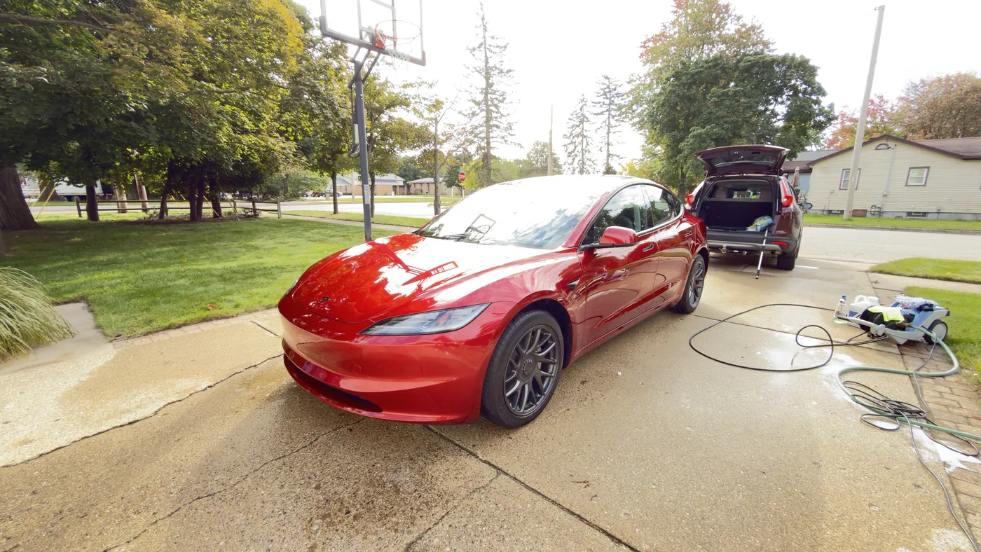 Red Tesla Model 3 in a driveway in Grand Haven, MI with detailing equipment set up for a 10-year ceramic coating