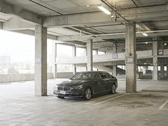 Dark BMW 7 Series parked on a level of a multi-level parking garage