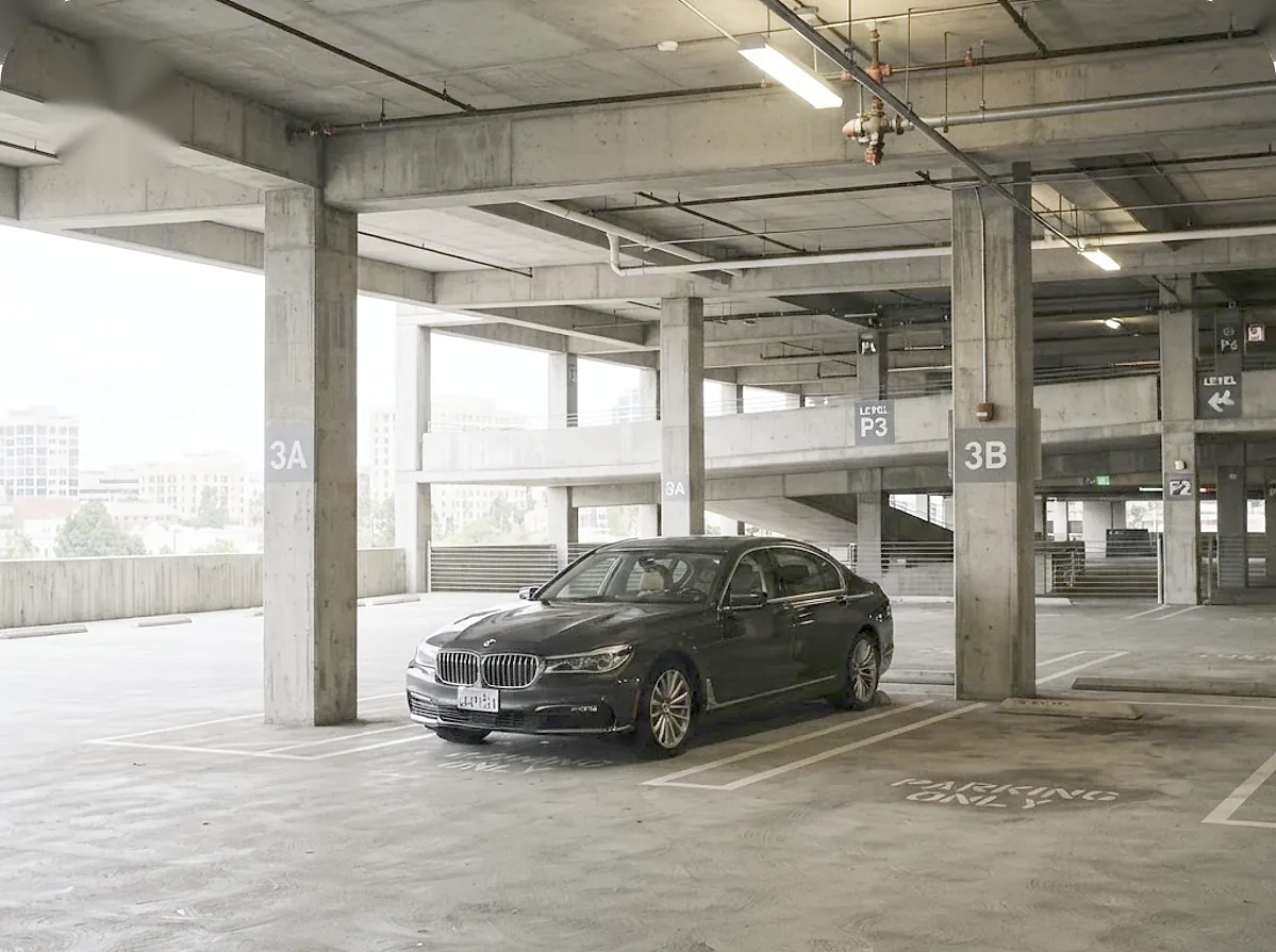 Dark BMW 7 Series parked on a level of a multi-level parking garage